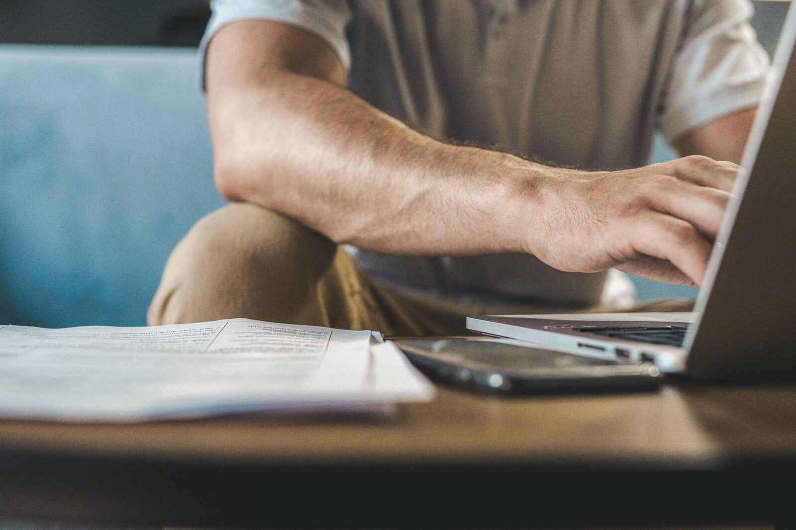 A man typing on a laptop at home, using wireless technology.